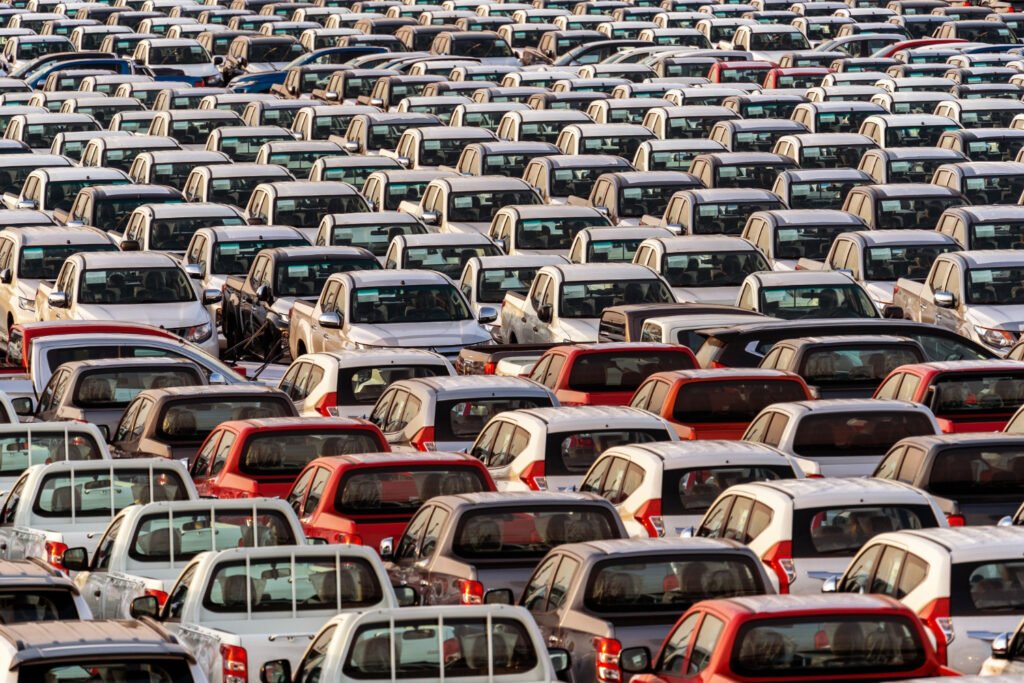 A imagem mostra um pátio cheio de carros enfileirados.