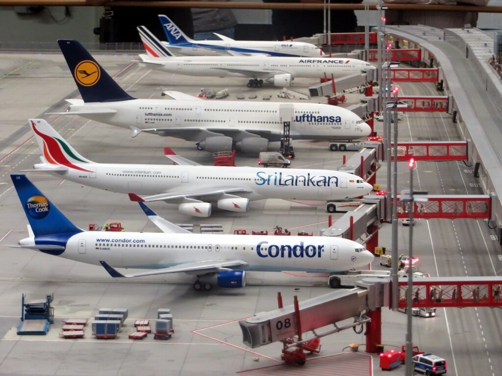 Cinco aeronaves estão estacionadas lado a lado em uma pista de aeroporto.